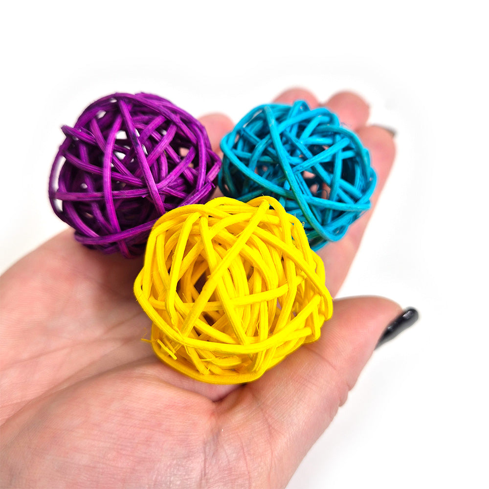 Eduk8 Multi Coloured Rattan Sensory Balls in purple, blue, and yellow shown in a child’s hand – tactile resource for sensory play and fine motor skill development.
